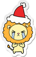 hand drawn sticker cartoon of a crying lion wearing santa hat