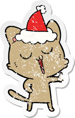 hand drawn distressed sticker cartoon of a cat singing wearing santa hat