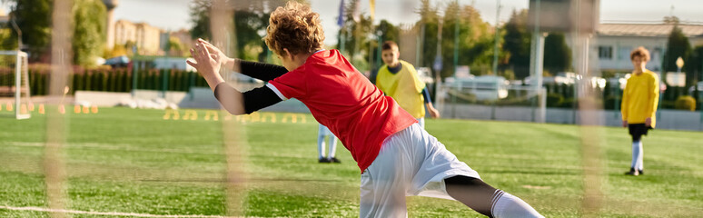 A vibrant group of young men enthusiastically engage in a spirited game of soccer on a green field...