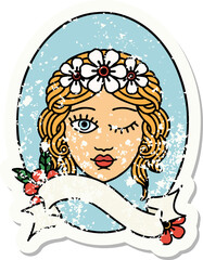 worn old sticker with banner of a maiden with crown of flowers winking