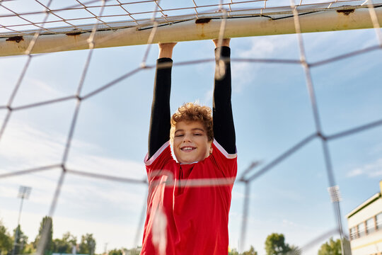 A talented young boy in a vibrant red shirt enthusiastically plays soccer, kicking the ball with precision and skill on a green grass field.