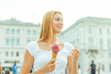 A young white woman eats ice cream and is happy during summer