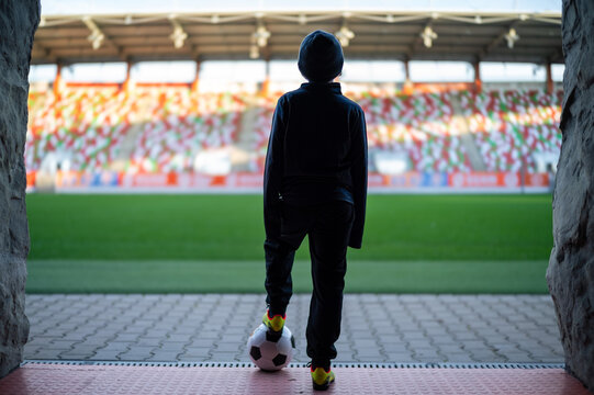 Young the boy with the ball standing in the players' tunnel and looking at the stadium