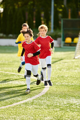 A group of young children, full of energy and excitement, sprint across the soccer field while...