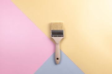 Top view of paint brush on colourful background. Blue, pink and yellow background. Colourful wallpaper, flat lay, copy space.