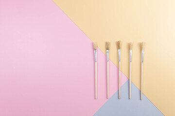 Obraz premium Top view of paint brushes on colourful background. Blue, pink and yellow background. Colourful wallpaper, flat lay, copy space.