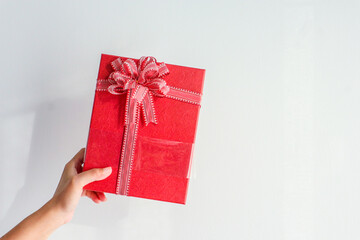 Young woman holding gift box with red satin ribbon bow.