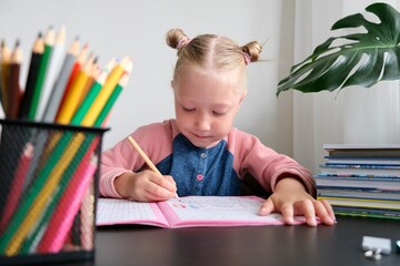 A preschool child learns to write in a workbook at home. The concept of home schooling 
