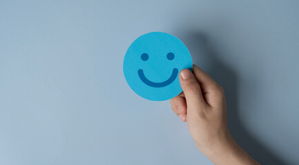 good feedback concept, paper cut smiley face in hands on light blue background. positive thinking, assessment and world mental health day.