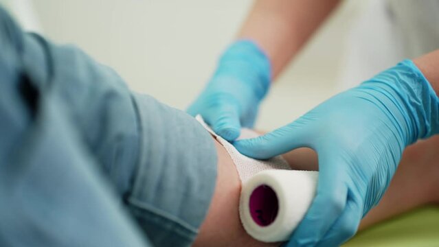 Closeup of unrecognizable nurse tying the bandage arm patient after drawing blood for analysis. Laboratory worker apply bandage on young man arm vein after blood test or injection of vaccine, slowmo.