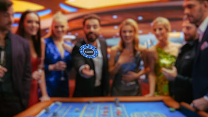 Cheerful Group of Rich People Gathered Around a Roulette Table at a Modern Casino. A handsome...