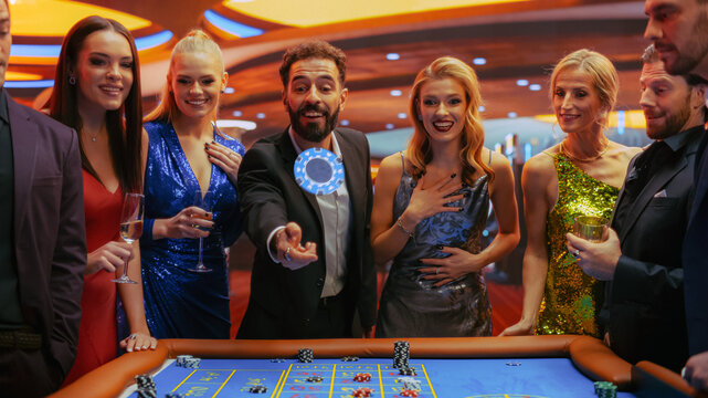 Casino Players Making Bets at a Roulette Table. Vibrant Crowd of International People Enjoying Nightlife in a City. Male Gambler Tossing a Casino Chip with a Template Placeholder Flying At the Camera