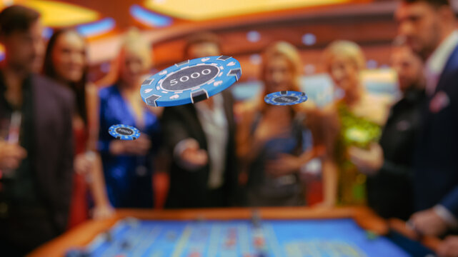 VFX Edit with a Gambler Tossing Three Casino Chips in Front of the Camera. Diverse People Playing, Placing Bets on a Roulette. Successful Men and Women Partying in a Casino, Enjoying Drinks.