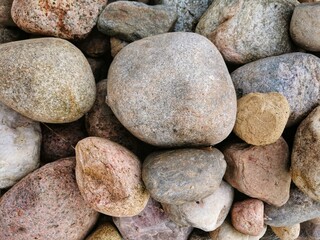 Fototapeta na wymiar Background, pattern, texture, with of large and small stones of pink, red, yellow, orange, beige and other colors, each stone has a different shape