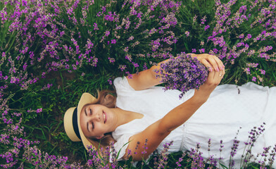 beautiful girl in a dress holding a bouquet of flowers outdoors in a lavender field in summer.