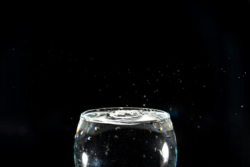 Transparent glass bowl filled with water with splashes of water around it. Splash Effect.
