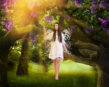 Fairy walking in magic forest. Girl with butterfly wings among trees