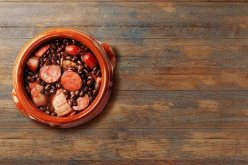Brazilian feijoada, traditional food from Brazil cuisine, on ceramic casserole bowl, over rustic wooden table. Copy space