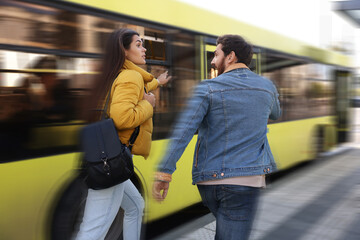 Being late. Couple running after bus outdoors. Motion blur effect