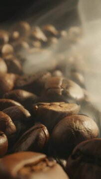 Roasting coffee beans with smoke on dark background. Smoke comes from fresh coffee seeds. Slider Macro vertical shot