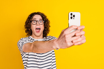 Photo portrait of nice teenager man hold gadget astonished reaction dressed stylish striped clothes...