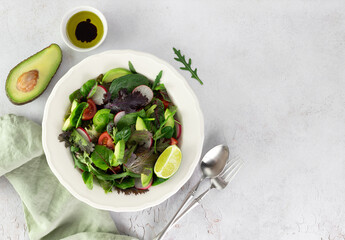 Fresh mix salad with avocado, tomato and radish on a white background. Avocado salad. Top view. Copy space.