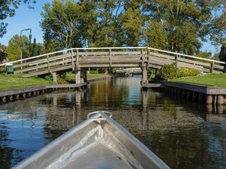 Image of a bridge above the gracht surrounded with trees and nature in Giethoorn, Netherlands