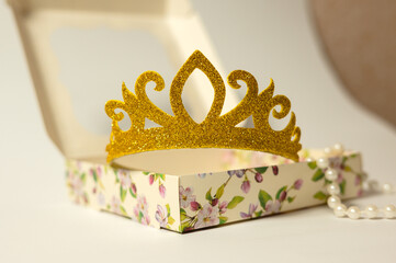 Toy crown and pearl necklace in cardboard box