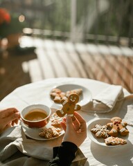 Vertical shot of female hands holding a christmas gingerbread man and a cup of coffee