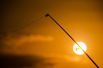 Silhouette Fishing Rod on the sun disk at Orange Sunset