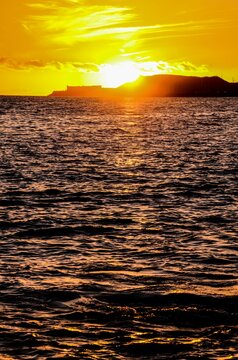 Vertical view of water waves before the hill under the sunset sky