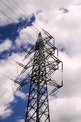 Low angle shot High Voltage Electric Transmission Tower against a cloudy blue sky