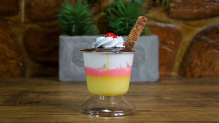 Close-up shot of delicious dessert with nougat, cherry and biscuit on a glass cup
