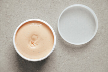 One jar and white cap with body cream or clay on concrete background, top view