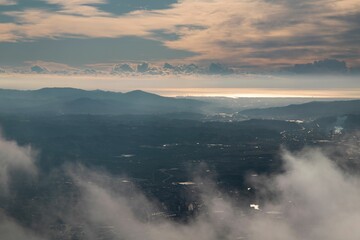 Aerial shot of the clouds and high rocky mountains in the background