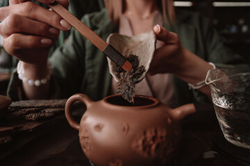 A tea master prepares for a tea ceremony. The setting is serene with multiple teapots in the...