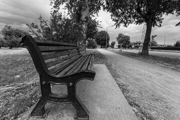 View of a wooden bench in a park shot in grayscale