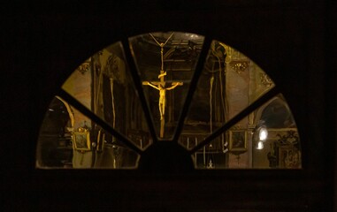 Figure of Jesus Christ on a cross hanging in a church captured from behind a glass window