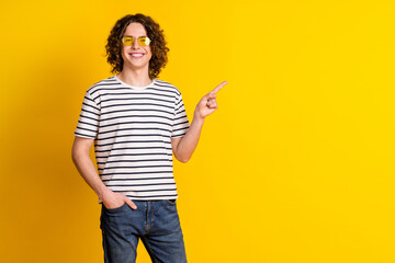 Photo of nice young man indicate finger empty space wear striped t-shirt isolated on yellow color...