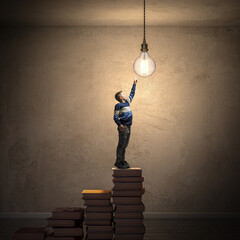 Aspiring young mind reaching for lightbulb on books
