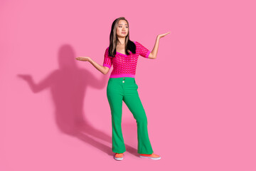 Full length photo of unsure uncertain lady dressed knitted shirt comparing arms looking emtpy space isolated pink color background
