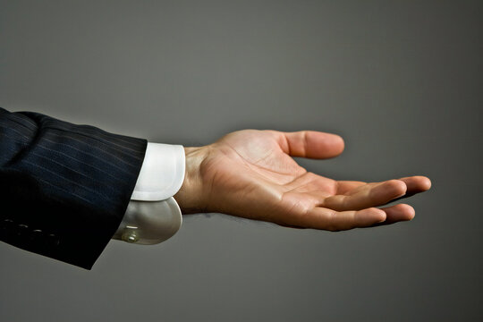 A businessman extends his hand with palm up. Product presentation or display 