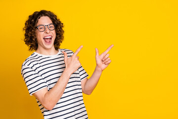 Portrait of overjoyed crazy young positive guy directing empty space announce new opening courses isolated on yellow color background