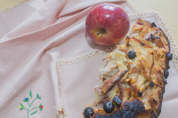 Homemade apple cake with raisins and fresh apples on wooden table