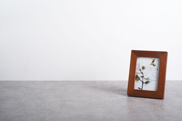 Closeup of a photo frame on a table against a white wall