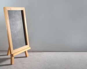 Closeup of a blank blackboard with a wooden frame against a gray background