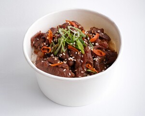 Closeup of a delicious spicy beef and rice bowl in a paper cup on a white surface