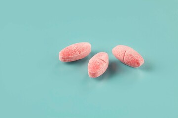 Closeup shot of three pieces of medicine in the form of pink caplets