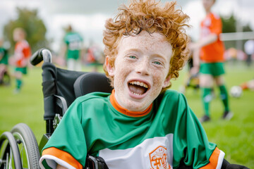 Portrait of a happy red-haired boy in a wheelchair playing soccer
