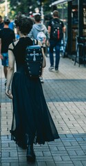 Vertical shot of a goth girl walking down the street with a coffin-shaped backpack.